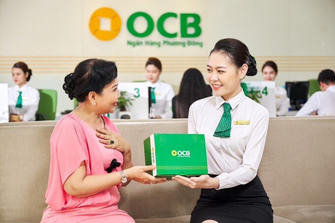 Nhân viên OCB trao quà tặng cho khách trong chuỗi chương trình ưu đãi kỷ niệm 25 năm thành lập. Ảnh: OCB